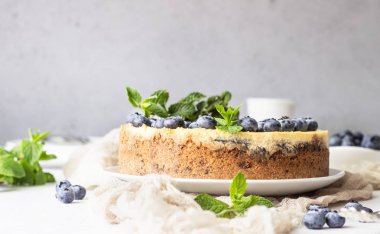 New York tarzı cheesecake, taze yaban mersini ve nane beyaz bir tabak ta. Açık taş arka plan. Kopyalama alanı.
