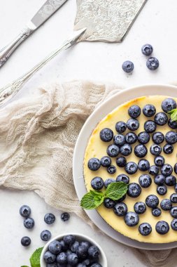 New York tarzı cheesecake, taze yaban mersini ve nane beyaz bir tabak ta. Açık taş arka plan. Kopyalama alanı.