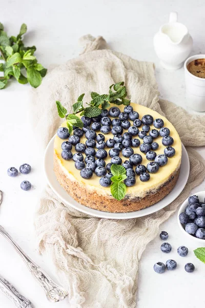New York tarzı cheesecake, taze yaban mersini ve nane beyaz bir tabak ta. Açık taş arka plan. Kopyalama alanı.