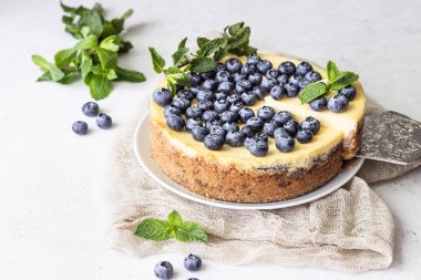New York tarzı cheesecake, taze yaban mersini ve nane beyaz bir tabak ta. Açık taş arka plan. Kopyalama alanı.