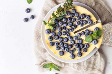 New York tarzı cheesecake, taze yaban mersini ve nane beyaz bir tabak ta. Açık taş arka plan. Kopyalama alanı.
