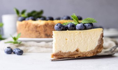 New York tarzı cheesecake, taze yaban mersini ve nane beyaz bir tabak ta. Açık taş arka plan. Kopyalama alanı.