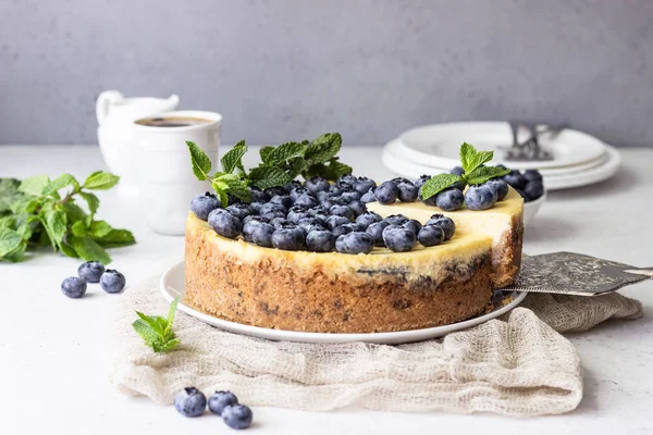 New York tarzı cheesecake, taze yaban mersini ve nane beyaz bir tabak ta. Açık taş arka plan. Kopyalama alanı.