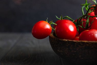 Taze kiraz domates ve fesleğen bir ahşap plaka karanlık bir arka planda. Hasat domates. 