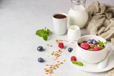 Süt, taze çilek (yaban mersini ve ahududu) ve süt ile ev yapımı granola Beyaz seramik kase. Sağlıklı kahvaltı malzemeleri. 