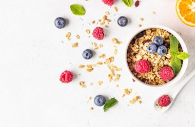 Sağlıklı kahvaltı malzemeleri. Süt, taze çilek (yaban mersini ve ahududu), portakal ve süt ile ev yapımı granola Kase. 