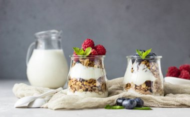 Taş gri masada granola, çilek ve yoğurt yapılmış lezzetli parfe ile Kavanozlar. Kopyalama alanı.