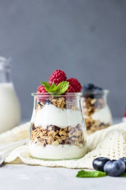 Taş gri masada granola, çilek ve yoğurt yapılmış lezzetli parfe ile Kavanozlar. Kopyalama alanı.