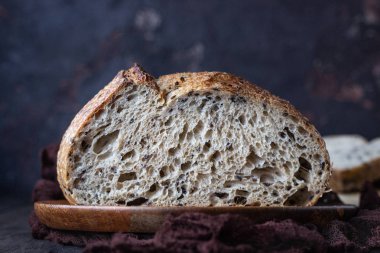 Ahşap bir tepside tohumları ile Geleneksel yuvarlak esnaf çavdar ekmeği somun. Koyu arka plan. 