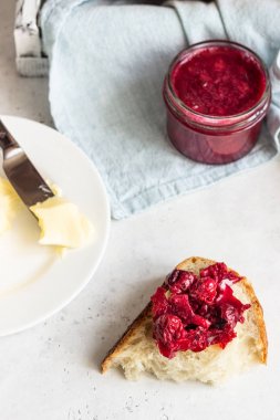 Açık gri taş masada tereyağı ve reçel ile tost beyaz esnaf ekmek. Sade kahvaltı.