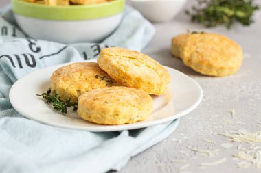 Beyaz seramik tabakta peynir ve kekik ile tuzlu çörekler veya kurabiyeler. Açık gri beton arka plan. 