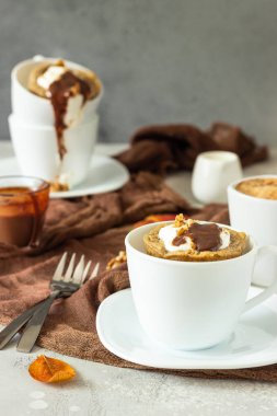 Beyaz bir seramik kupa krem şanti, karamel sos ve ceviz ile Havuç veya kabak kupa cupcake. Rahat sonbahar veya kış kahvaltısı. Sağlıklı tatlı. 
