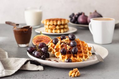Karamel soslu geleneksel Belçika waffle'ları, üzüm ve incir. Rahat sonbahar veya kış kahvaltısı. İyi hissetmek için yenen yemek.