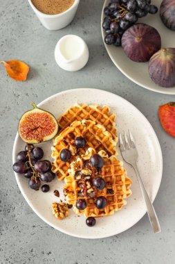 Karamel soslu geleneksel Belçika waffle'ları, üzüm ve incir. Rahat sonbahar veya kış kahvaltısı. İyi hissetmek için yenen yemek.