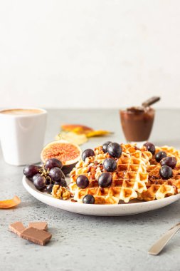 Karamel soslu geleneksel Belçika waffle'ları, üzüm ve incir. Rahat sonbahar veya kış kahvaltısı. İyi hissetmek için yenen yemek.