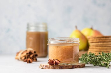 Cam kavanozda baharatlı armut reçeli, taze armut, baharat (tarçın ve anason) ve kekik.