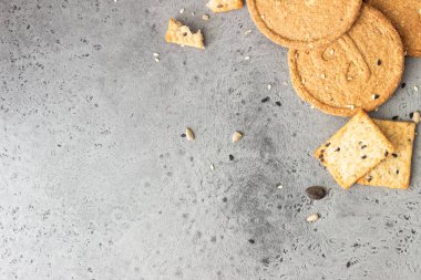 Gri beton arka plan üzerinde tohumları ile ince gevrek kepekli kraker. 