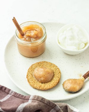 Gri bir tabak üzerinde doğal yoğurt ve reçel ile ince gevrek kepekli kraker. Sade kahvaltı veya atıştırmalık. 