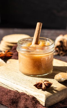 Cam kavanozda baharatlı armut reçeli, kraker, baharat (tarçın ve anason) ve kekik. Kahverengi taş arka plan. Rustik stil.