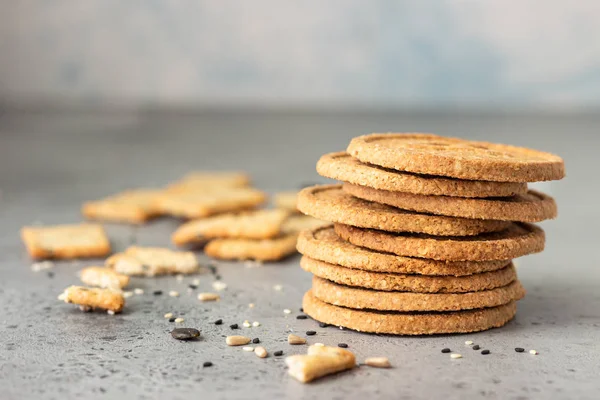 Gri beton arka plan üzerinde tohumları ile ince gevrek kepekli kraker. 