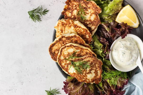 Vegetable (cauliflower) pancakes (fritters) with natural yogurt dressing and dill.