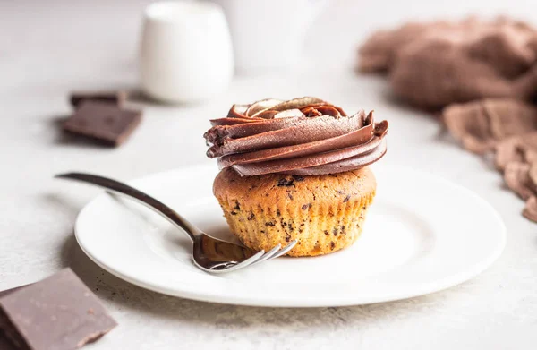Cupcake or muffin with chocolate with chocolate swirl icing on light grey background. Delicious dessert.