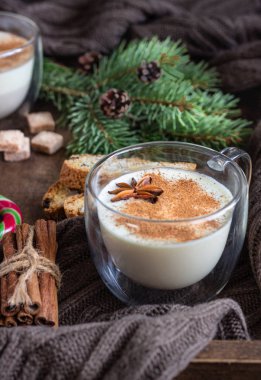 Eggnog. Tarçın ile Noel süt kokteyli, biscotti çerezleri, kış baharat, şeker ve köknar dalı ile ahşap tepsi üzerinde iki cam kupalar servis.