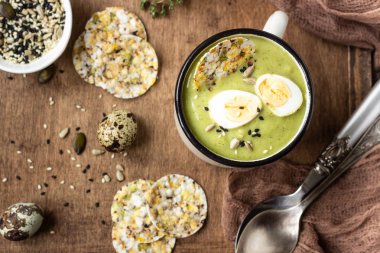 Bıldırcın yumurtası, kraker ve tohum karışımı ile yeşil brokoli krem çorba ahşap bir tepsiüzerinde. Üst te. Sağlıklı beslenme.
