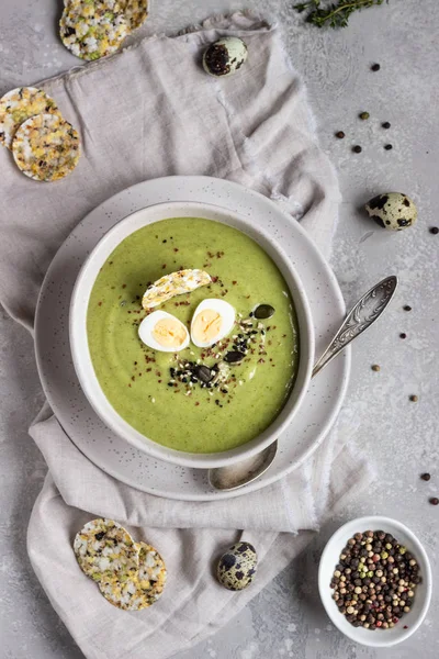 Detox broccoli green cream soup with seed mix, quail egg and crackers in bowl on light grey stone background. Top view. Healthy food concept. — Stock Image Detox Broccoli Green Cream Soup Seed Mix Quail Egg Crackers Stock Picture