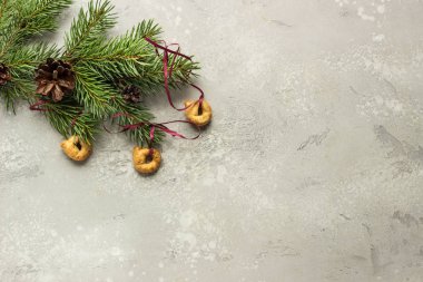 Tarallini or Taralli and fir branches and cones. Traditional Italian snack on a grey stone background. Christmas and New Year concept. clipart