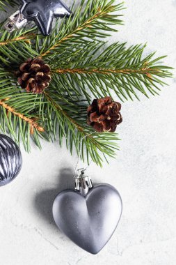 Noel tebrik kartı, yeni yıl ağacı dalları, koniler ve Noel süslemeleri. Selamlarınız için uzayı kopyalayın. Şenlik arka planı. Açık mavi beton arkaplan.