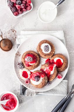 Çikolatalı süzme peynirli krep veya ekşi kremalı börek ve donmuş böğürtlen (ahududu ve böğürtlen). Geleneksel Ukrayna mutfağı. Syrniki. Sağlıklı ve diyet kahvaltı veya tatlı.