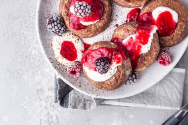 Çikolatalı süzme peynirli krep veya ekşi kremalı börek ve donmuş böğürtlen (ahududu ve böğürtlen). Geleneksel Ukrayna mutfağı. Syrniki. Sağlıklı ve diyet kahvaltı veya tatlı.