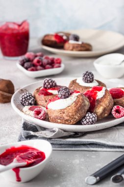 Çikolatalı süzme peynirli krep veya ekşi kremalı börek ve donmuş böğürtlen (ahududu ve böğürtlen). Geleneksel Ukrayna mutfağı. Syrniki. Sağlıklı ve diyet kahvaltı veya tatlı.