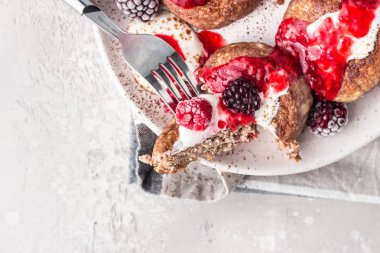 Çikolatalı süzme peynirli krep veya ekşi kremalı börek ve donmuş böğürtlen (ahududu ve böğürtlen). Geleneksel Ukrayna mutfağı. Syrniki. Sağlıklı ve diyet kahvaltı veya tatlı.