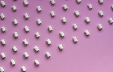 Pembe kağıtta beyaz lokum deseni. Renk arkaplanındaki beyaz şekerlemelerin geometrik deseni.