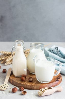 Alternative types of milks in glass bottles. Vegan nondairy milk. Assortment of organic vegan nondairy milk from nuts, oatmeal, seeds. clipart