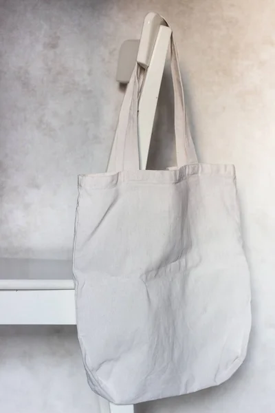 Blank canvas tote bag hanging on a chair. Handmade shopping bags. Reusable bag.