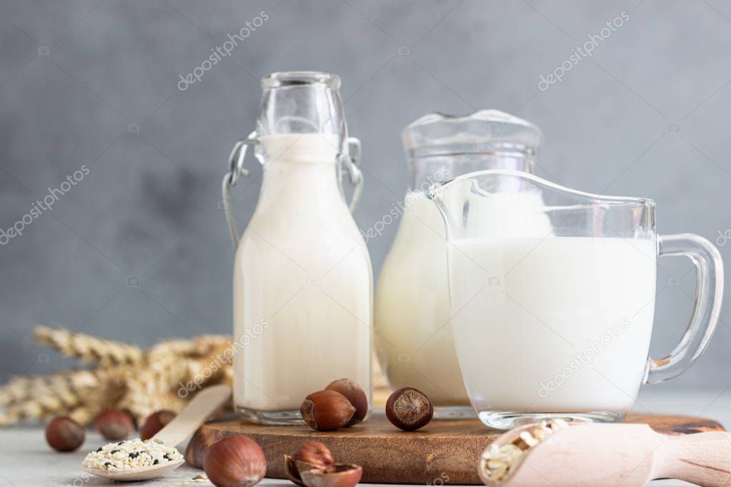 Alternative types of milks in glass bottles. Vegan nondairy milk. Assortment of organic vegan nondairy milk from nuts, oatmeal, seeds.