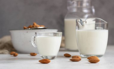 Açık gri arkaplanlı, cam sürahide organik badem sütü. Sağlıklı ve vejetaryen yemekleri. Alternatif süt türü.