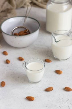 Açık gri arkaplanlı, cam sürahide organik badem sütü. Sağlıklı ve vejetaryen yemekleri. Alternatif süt türü.