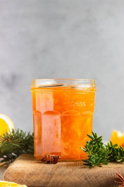 Noel hediyesi olarak cam kavanozda portakal kabuğu bulunan ev yapımı portakal reçeli veya köknar dalları, baharatlar (tarçın ve anason) ve portakal. Seçici odak.