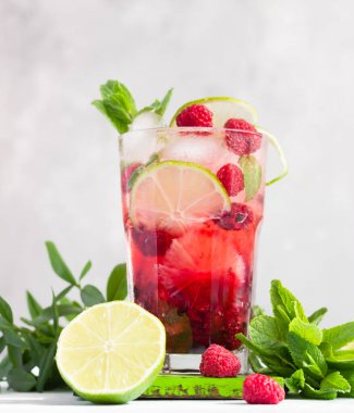 Pembe kokteyl ya da ahududulu limonata, nane, kireç ve buz gri beton bir masada. Yaz içeceği..