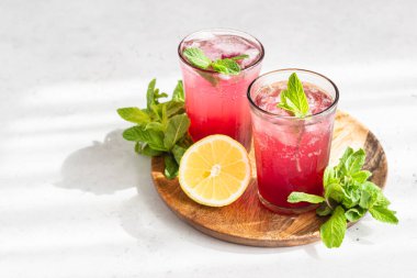 Soğuk, köpüklü amber çiçeği ya da karkade çayı, limon, nane ve buzlu gri taşlı arka planda. Yaz içeceği, limonata..
