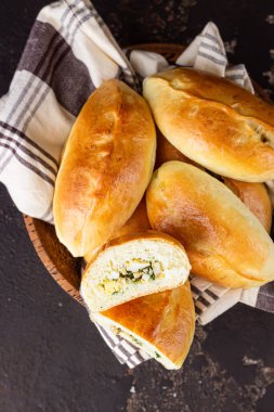 Geleneksel Rus turtaları, yeşil soğanlı ve ahşap tabakta yumurta, koyu kırsal arka plan. Rus pirozhki, ev yapımı köfteler..