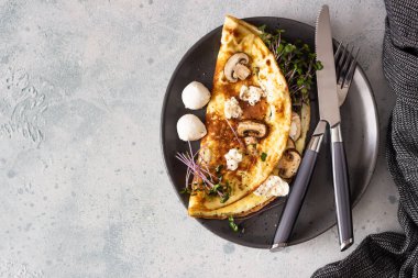 Mantarlı ev yapımı omlet, mozzarella ve tabakta hafif beton kaplama mikroyeşiller. Sağlıklı gıda konsepti.