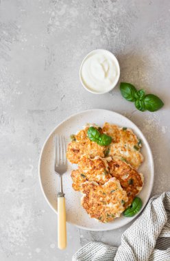 Seramik bir tabakta fesleğen ve ekşi kremayla sulu ev yapımı tavuk pirzolası. Açık gri arkaplan. Üst görünüm.