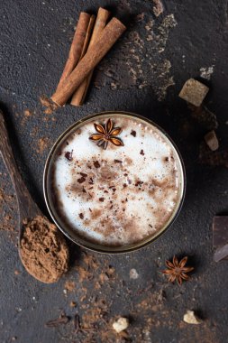 Bir fincan sıcak kakao ya da anason yıldızı ve tarçın çubuklu sıcak çikolata. Sonbahar ya da kış için geleneksel içecek. Karanlık arka plan. Üst görünüm.