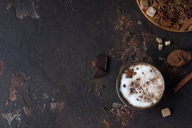 Ev yapımı baharatlı sıcak çikolata, anason yıldızı, tarçın çubukları ve acı çikolata, koyu kahverengi arka plan. Üst görünüm.
