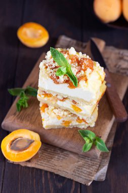 Lezzetli çiğ kayısılı cheesecake. Kesme tahtasında parçalanmış, koyu arka planda. Sağlıklı vejetaryen gıda kavramı.